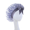 A purple satin wide-brimmed hair wrap headscarf tied with a bow displayed on a mannequin.