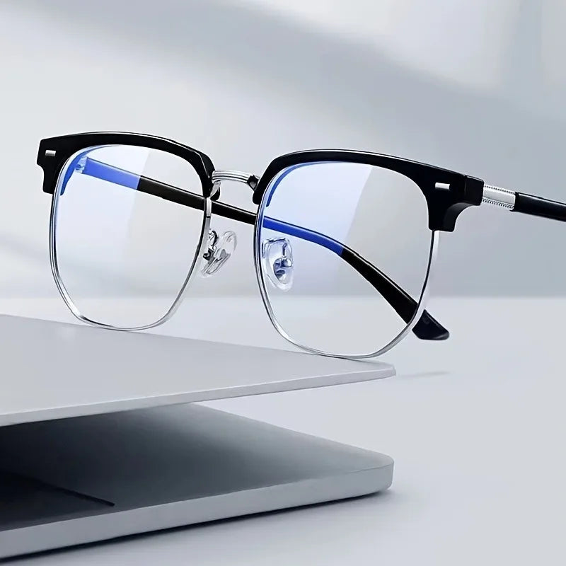 A pair of black and blue-rimmed retro half gold anti blue light eyeglasses resting on a white surface.