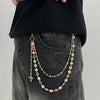 A gold pearl cross pendant necklace is displayed against a dark denim background.