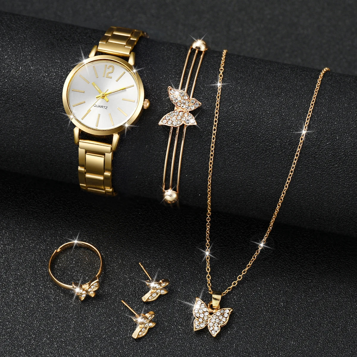 A set of elegant gold-toned quartz wrist watch, a delicate gold chain necklace, and three small gold butterfly rings displaye