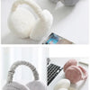 A collection of soft, plush fur ear warmers and earmuffs in shades of gray and pink are displayed on a white surface.