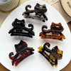 A set of five dark brown and amber colored cartoon animal hair clips displayed on a white plate.