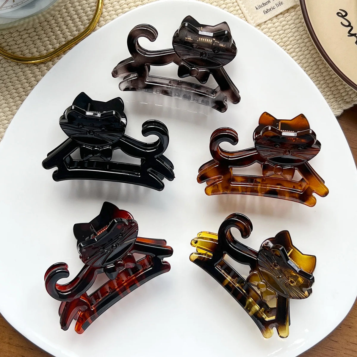 A set of five dark brown and amber colored cartoon animal hair clips displayed on a white plate.