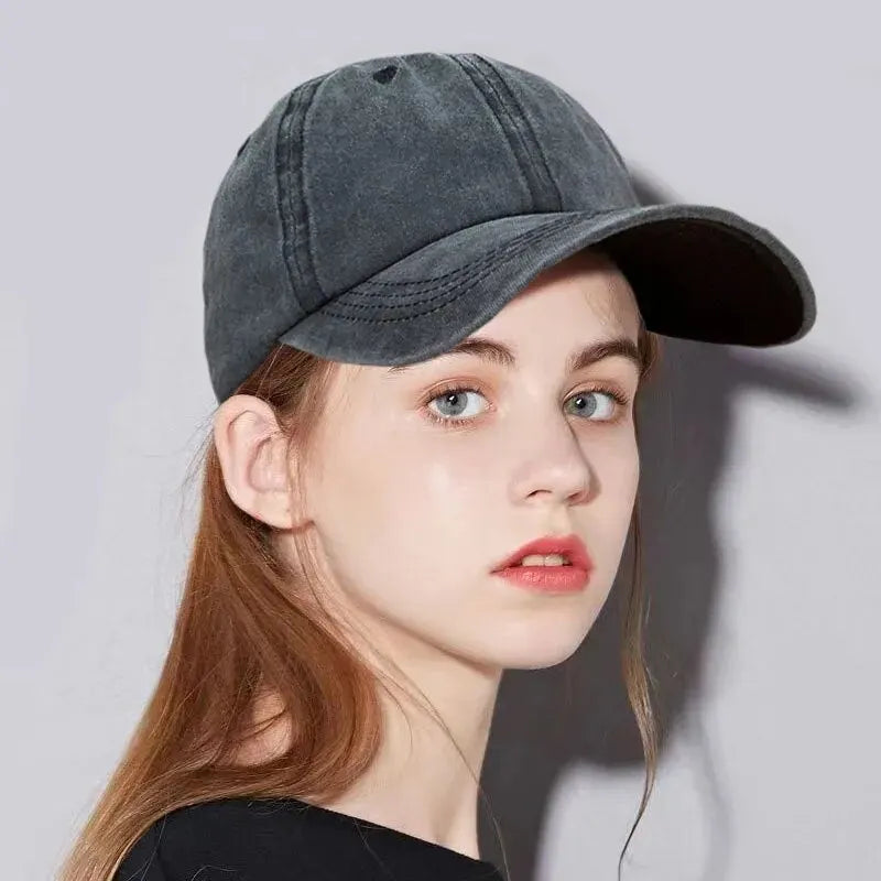 A close-up of a woman wearing a dark gray casual baseball cap.