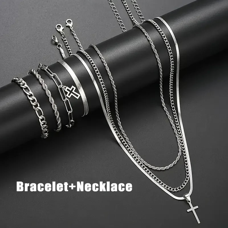 A collection of silver stainless steel bracelets and necklaces featuring cross designs displayed on a dark background.