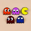 A set of four enamel pins shaped like Pac-Man in orange, purple, yellow, and blue.