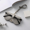 A light gray felt pouch with a black strap and gold hardware is shown next to an open notebook.