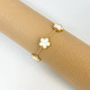 Gold plated stainless steel double-sided petal bracelet displayed on a beige textured background.