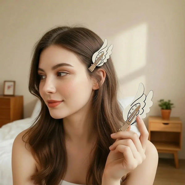 A woman with long brown hair is shown holding a pair of cute angel wing hair clips and barrettes.