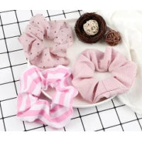 A pink knitted hair scrunchie headband product displayed on a white plate with a black grid background.