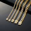 A close-up of several gold Cuban link chain necklaces displayed on a dark surface.