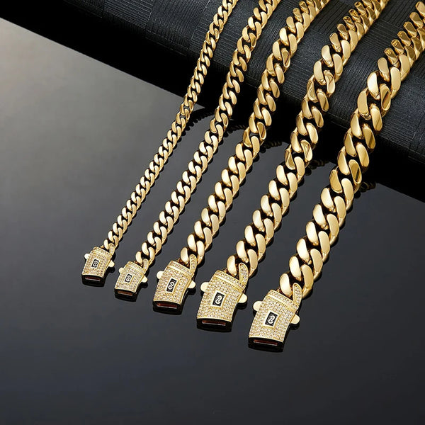 A close-up of several gold Cuban link chain necklaces displayed on a dark surface.