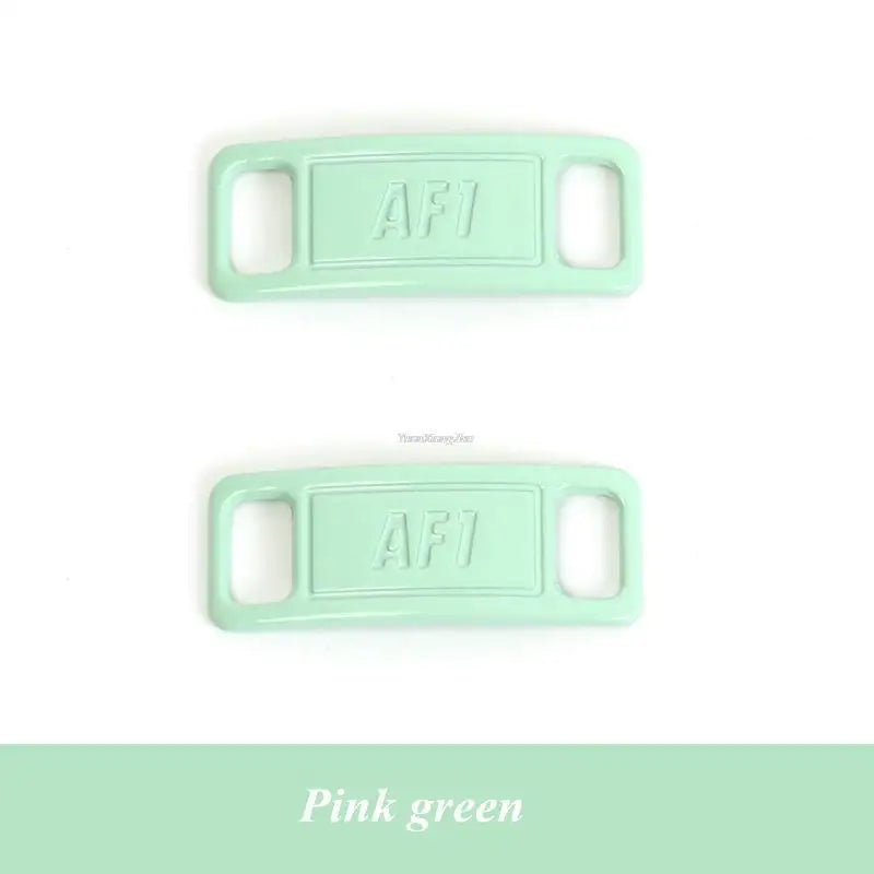 A pair of light mint green diamond shoe charms with the letters AFI stamped on them.