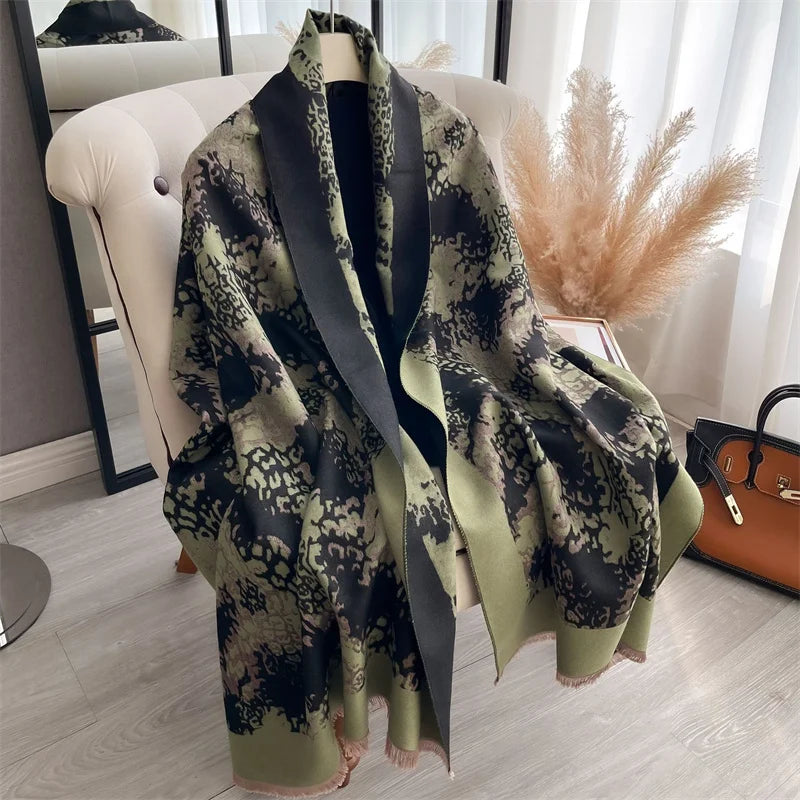 A draped olive green and black patterned cashmere scarf or shawl displayed on a white chair.