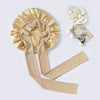 A beige silk sleep bonnet with a ruffled crown and matching satin straps, next to a small bowl of white hair accessories.