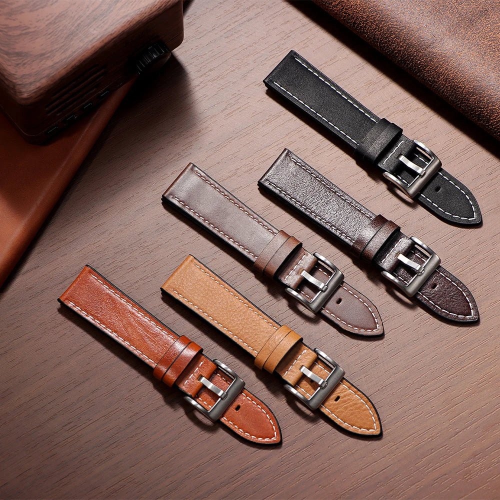 Three handmade calfskin leather watch straps in brown and black leather on a wooden surface.