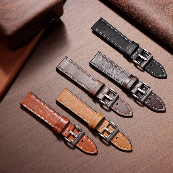 Three handmade calfskin leather watch straps in brown and black leather on a wooden surface.