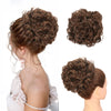 A woman's hair styled in a voluminous brown curly chignon or messy bun using a synthetic hairpiece.