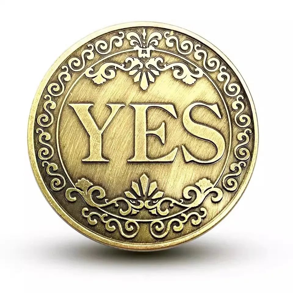 A round vintage antique bronze coin with the word YES embossed in the center surrounded by decorative scrollwork.