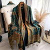 A dark teal and gold bohemian paisley tassel shawl draped over a hanger.