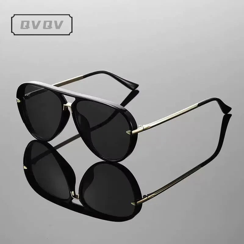 Une paire de lunettes de pilot noires avec une monture métallique vintage et des branches ton or.
