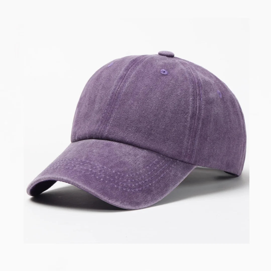 A purple washed cotton snapback cap shown from the side.