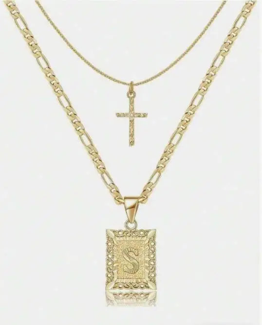 Collier pendentif de couleur or avec une lettre S et un motif croix.