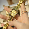 A hand is wearing a gold-toned minimalist quartz wristwatch on its wrist.