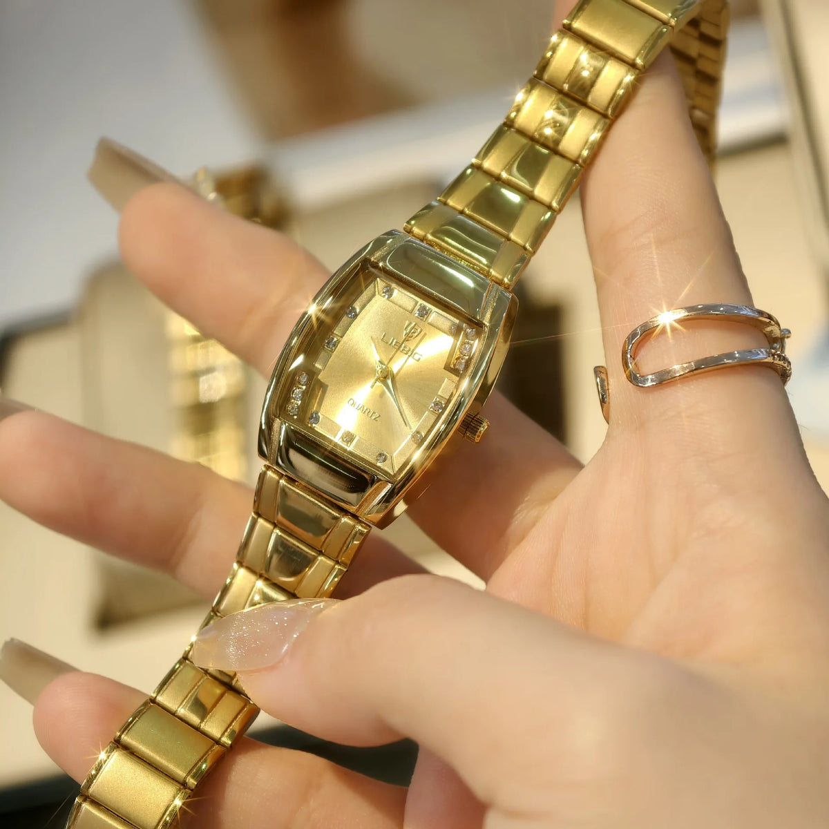 A hand is wearing a gold-toned minimalist quartz wristwatch on its wrist.