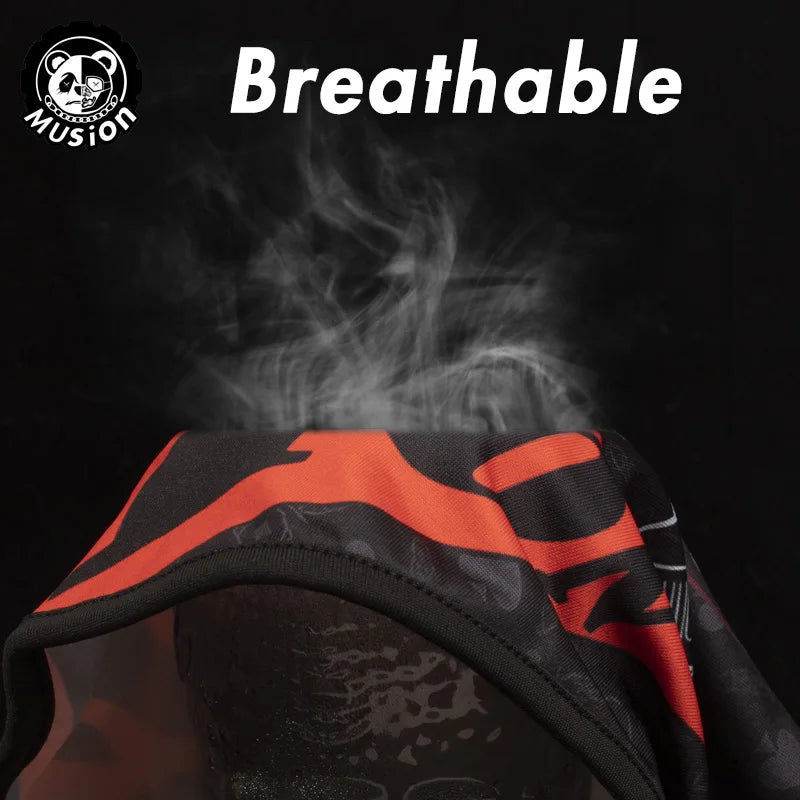 A close-up of an orange and black breathable full face balaclava helmet liner being shown on a dark background.