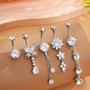 A set of five gold stainless steel dangled belly button rings with various diamond and floral designs displayed on a beige su