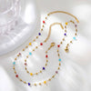 A gold chain necklace featuring irregular colored stones like red, yellow, blue, and purple.