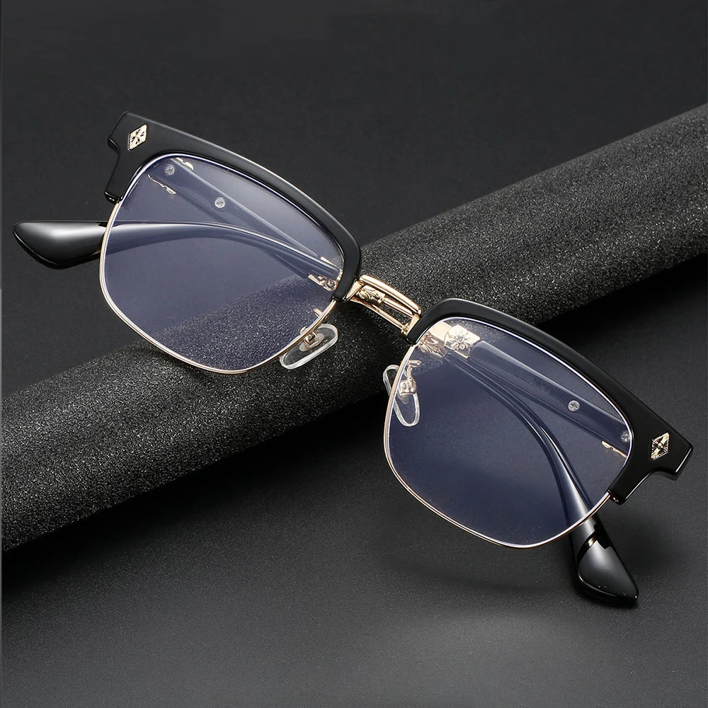 Une paire de lunettes vintage à demi-monture avec des verres bleu foncé et des accents dorés posées sur une surface noire.
