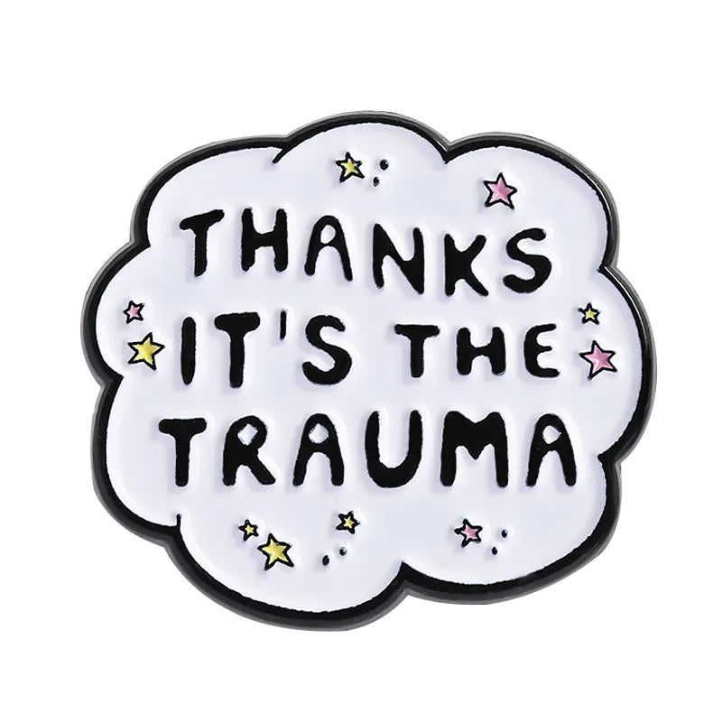 A white enamel lapel pin shaped like a cloud with black text reading Thanks It's the Trauma and small stars.