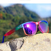 Purple and blue gradient square polarized sunglasses resting on a light-colored rock outdoors.