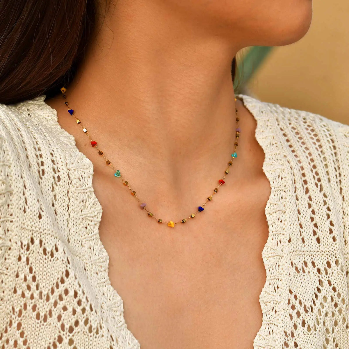 A close-up of a boho irregular stone choker necklace worn around the neck against a light knit garment.