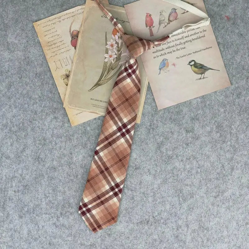 A plaid necktie is displayed alongside old papers and illustrations on a gray background.