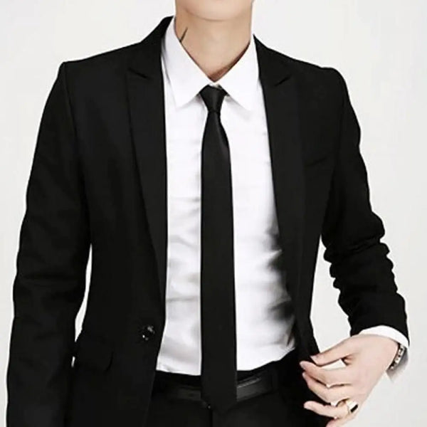 A man wearing a black suit jacket, white shirt, and black silk necktie.