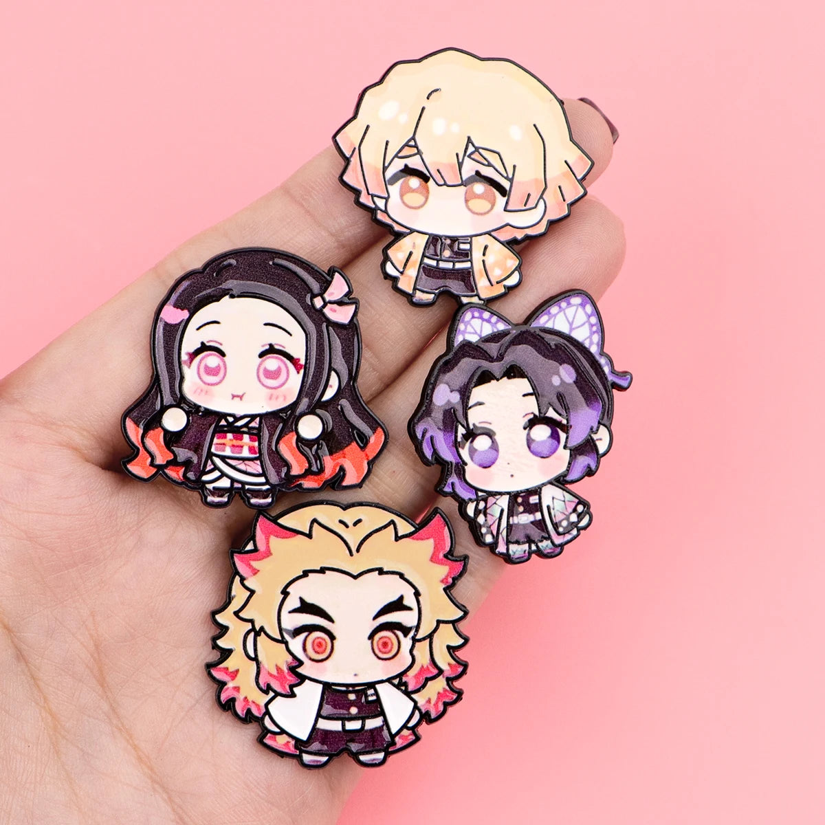 A hand holds a set of eight cute enamel cartoon brooches featuring various anime-style characters with pink and purple hair.