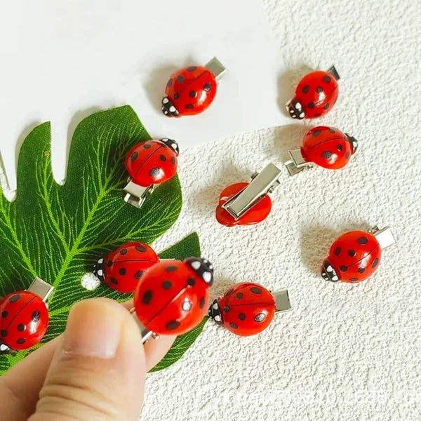 A set of ten cute ladybug hair clips in red and black dots arranged on a white background.