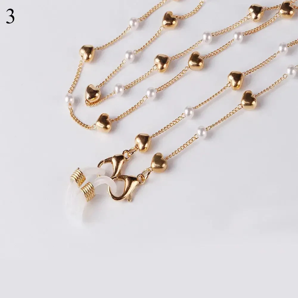 Gold and pearl chain lanyard jewelry displayed on a white background.