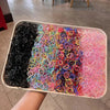 A tray filled with colorful disposable rubber hair ties in various shades of black, pink, yellow, and blue.