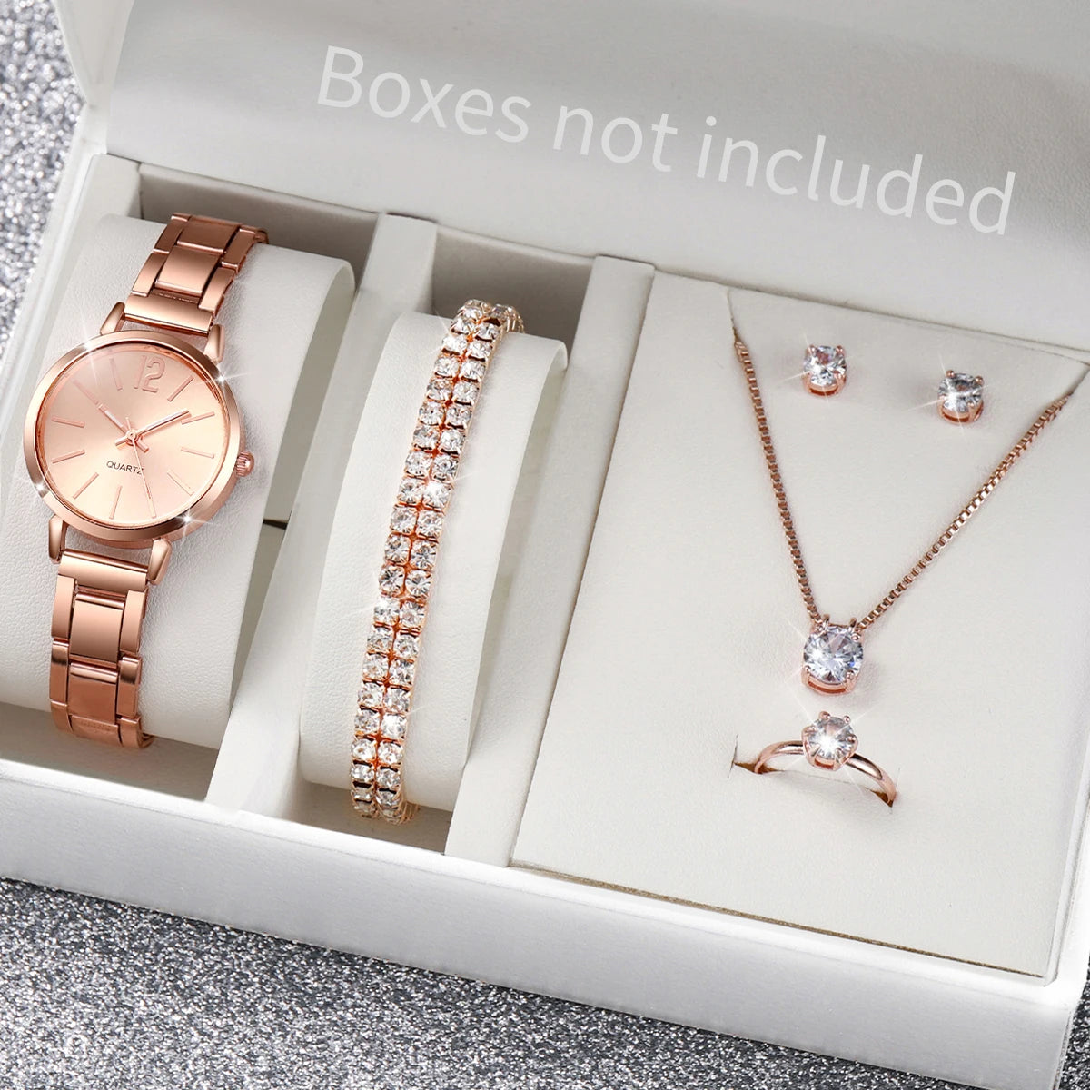 A box contains a rose gold quartz wrist watch, a matching bracelet, a necklace with a pendant, and a ring.