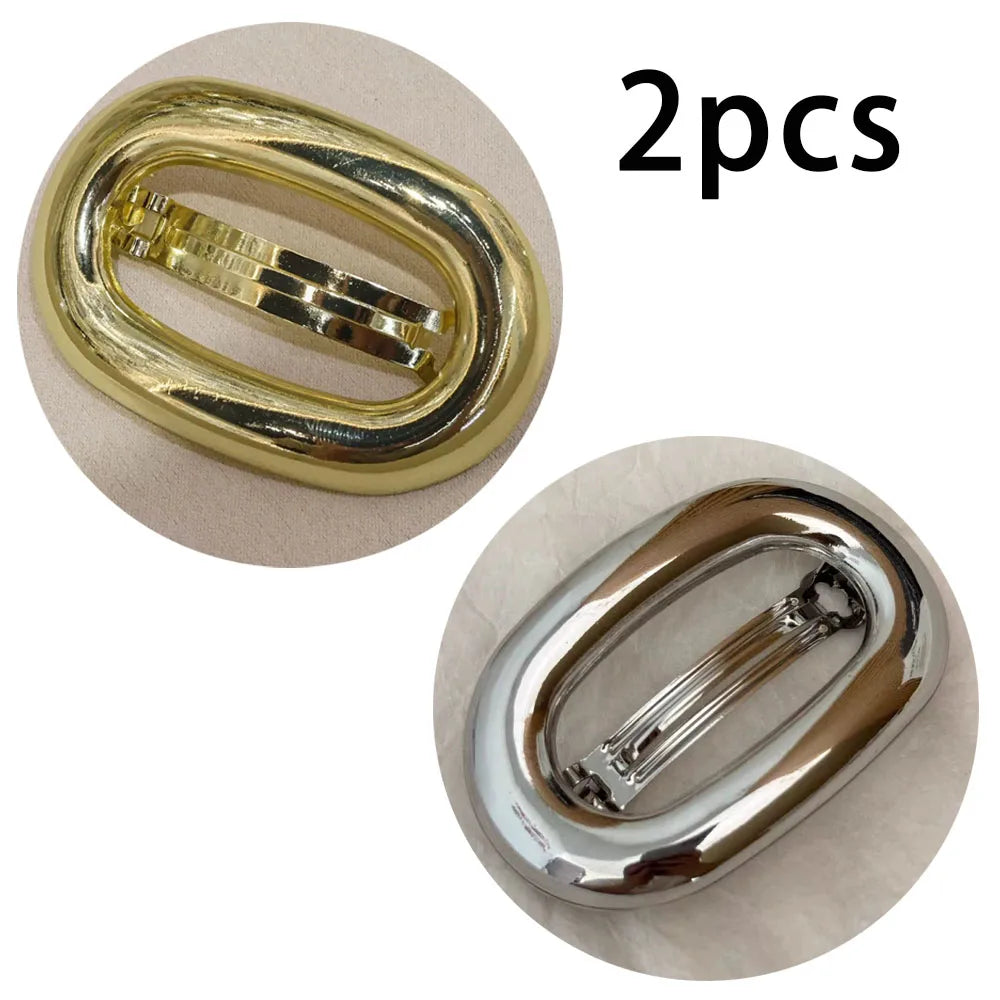 Two gold-colored metal oval hair clips shown in close-up view.