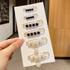 A display of gold-toned pearl brooch pins in various sizes and styles, including black and white pearls.