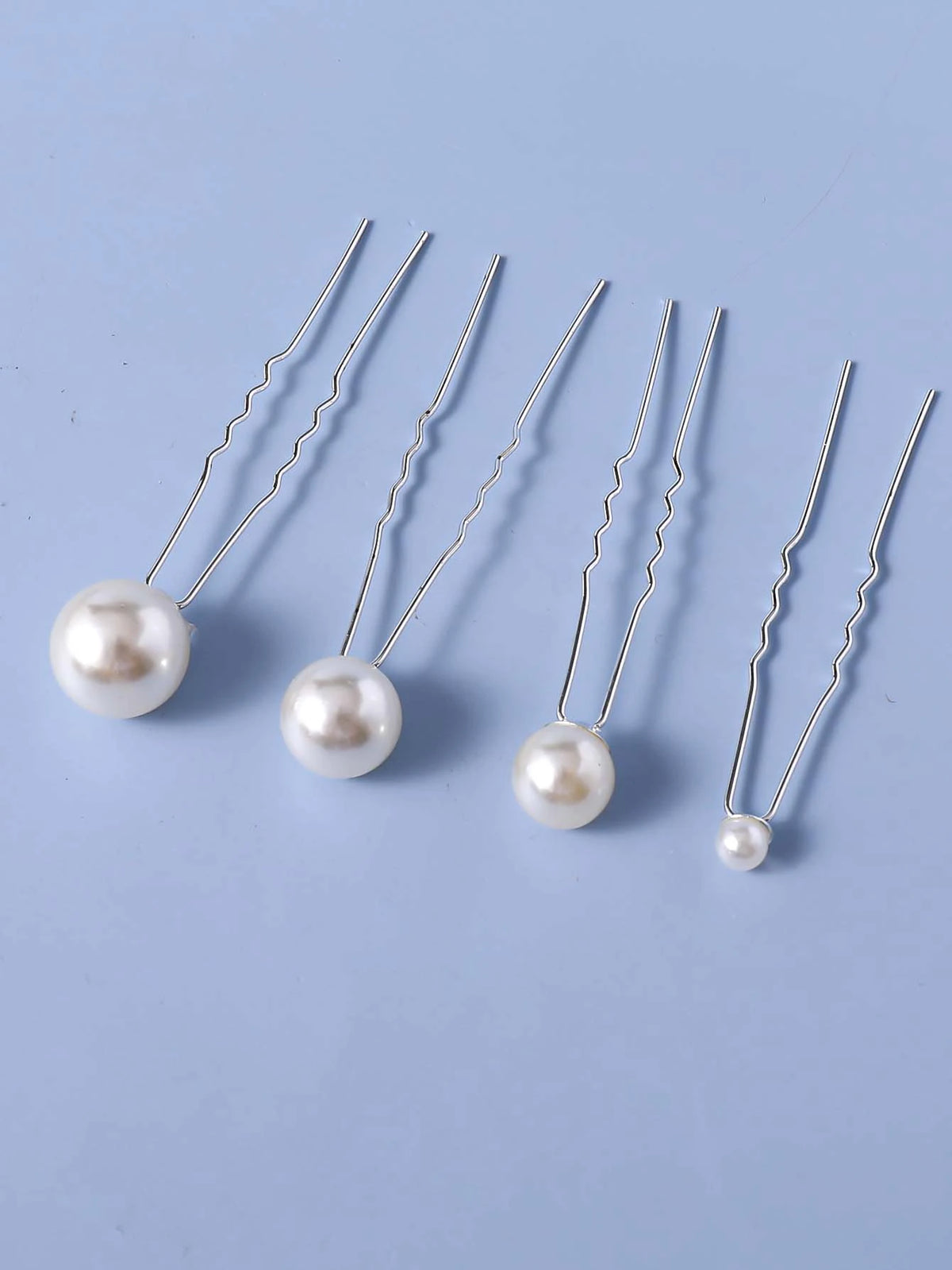 Eightteen faux pearl hair pins with silver wires displayed on a light blue background.