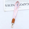 Rosa gemustertes Leder-Handy-Lanyard mit Messingverschluss an einem braunen Lederriemen.