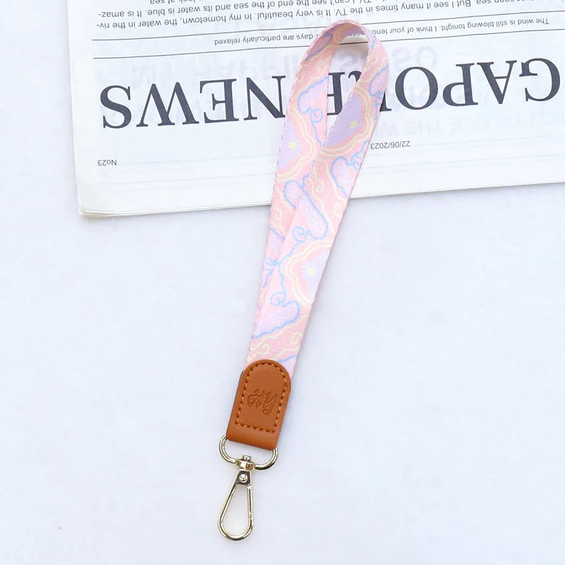 Rosa gemustertes Leder-Handy-Lanyard mit Messingverschluss an einem braunen Lederriemen.
