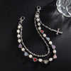 Silver chain necklace with white pearls and a cross pendant displayed on a black background.
