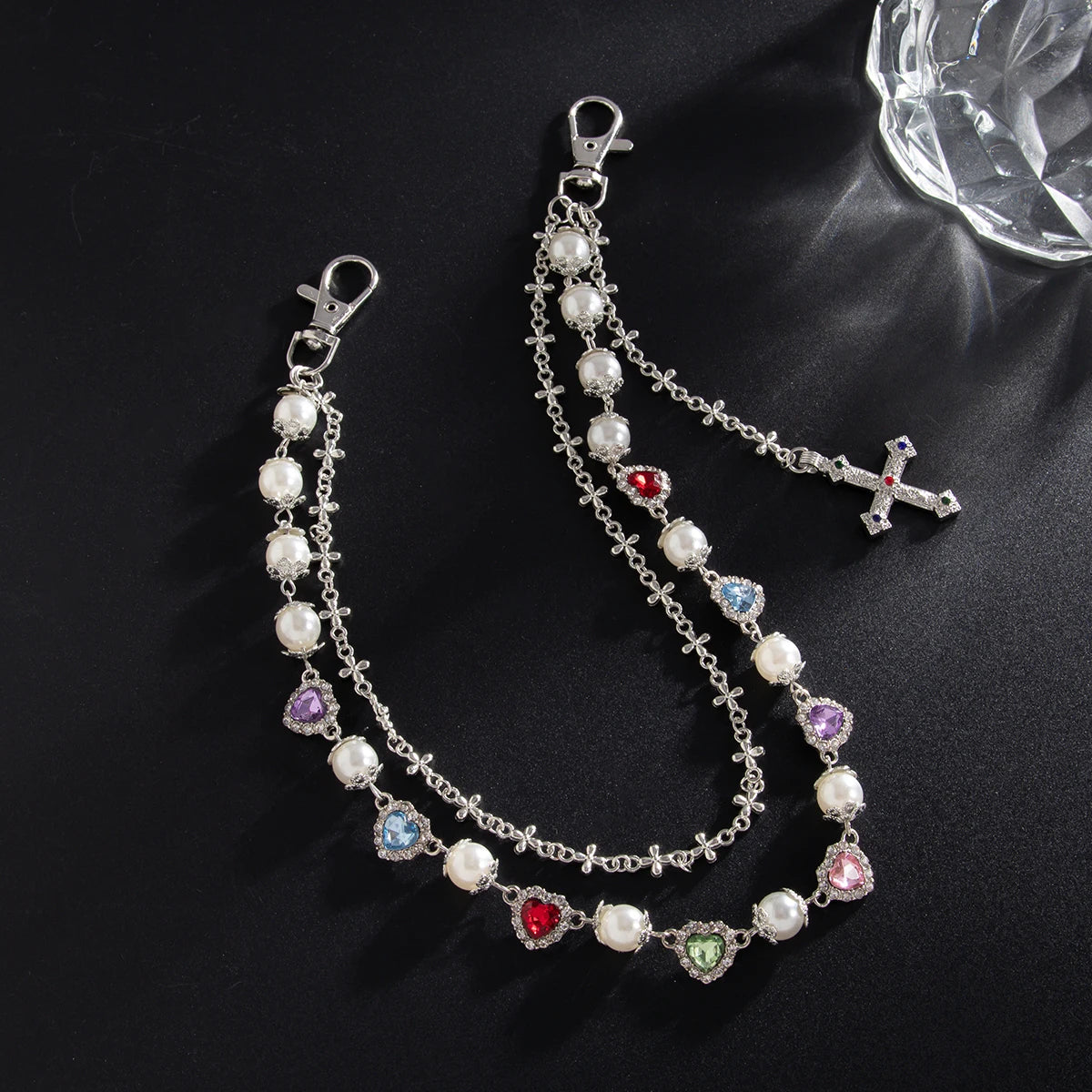 Silver chain necklace with white pearls and a cross pendant displayed on a black background.